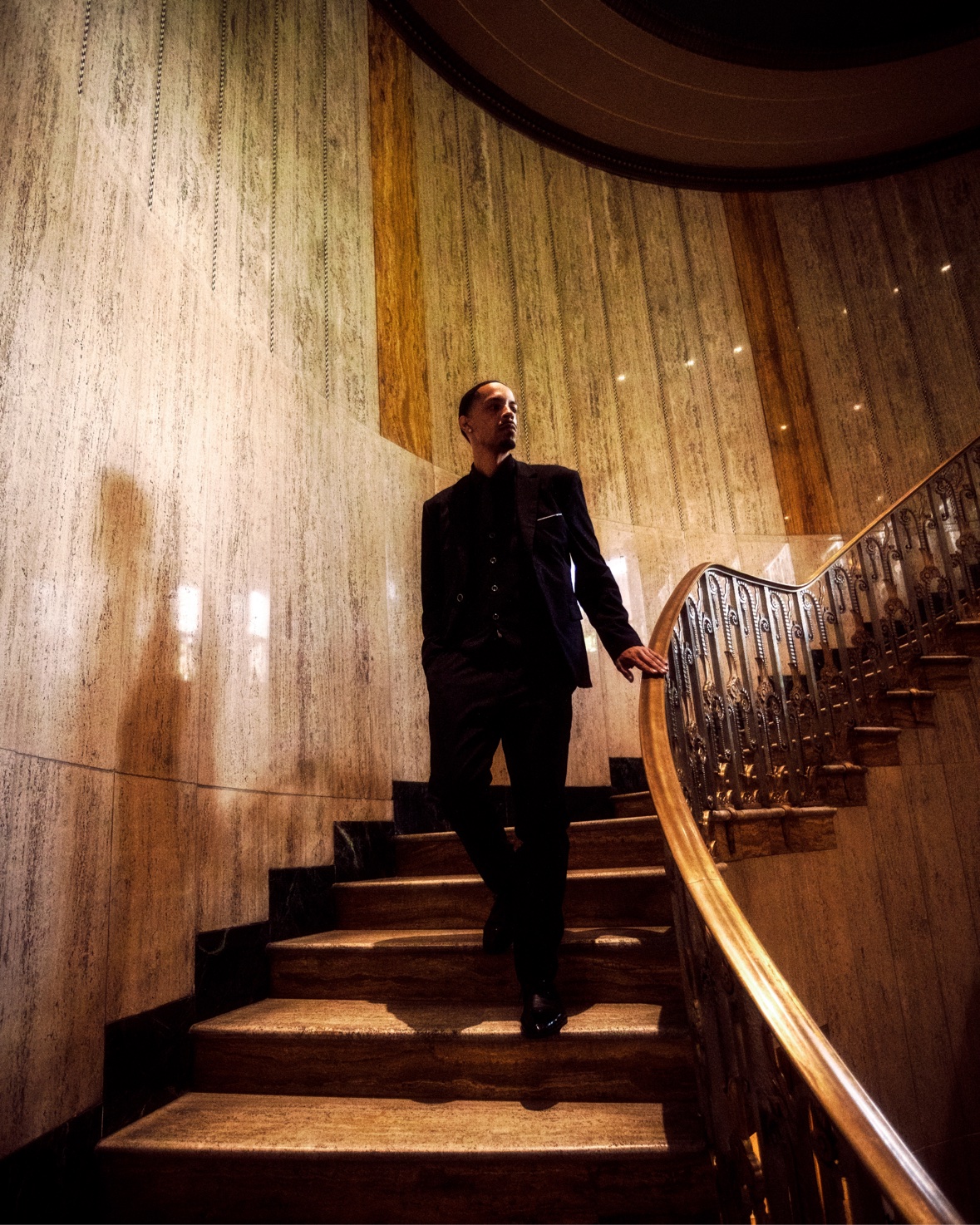Black suit descending marble staircase